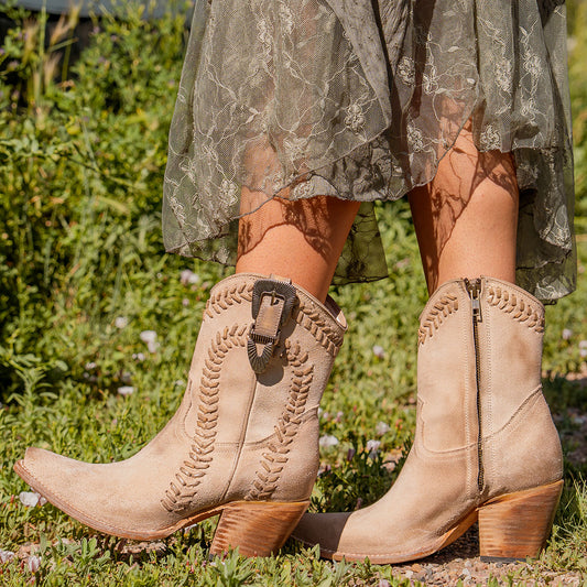 FREEBIRD women's Freya beige suede bootie with whip stitch detailing, a snip toe silhouette and decorative vintage buckle. Finished with an inside working zipper.
