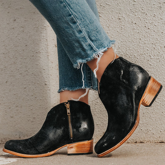 FREEBIRD women's Hippy black suede low heeled bootie with a working brass zip closure, heel seam embroidery, almond toe, and front dip detailing
