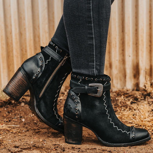 FREEBIRD women's Poppy black suede bootie with high heel, inside zip closure, decorative belt, and floral detailing