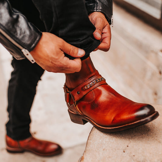 FREEBIRD men's Portland rust leather boot featuring a leather ankle harness with brass chainlink detail, a working inside zip closure and low block heel 