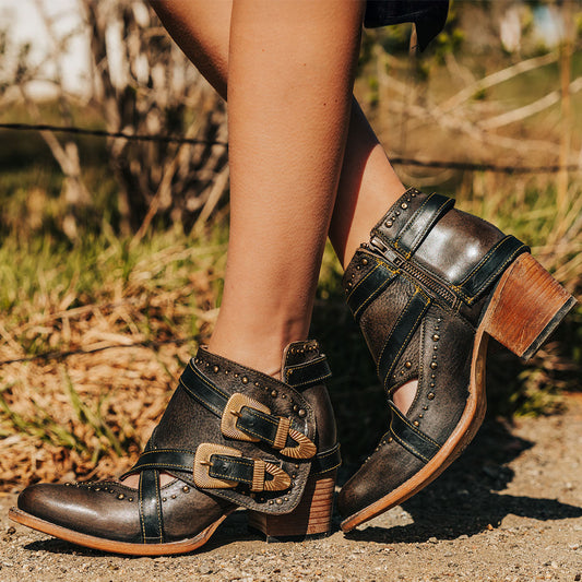 FREEBIRD women's Samantha black bootie with stud detailing, contrasting straps with gold hardware, and inside zip closure