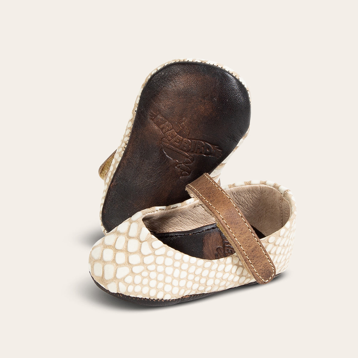 Side view showing leather strap detailing and soft leather imprinted sole on FREEBIRD infant baby Jane white snake leather shoe