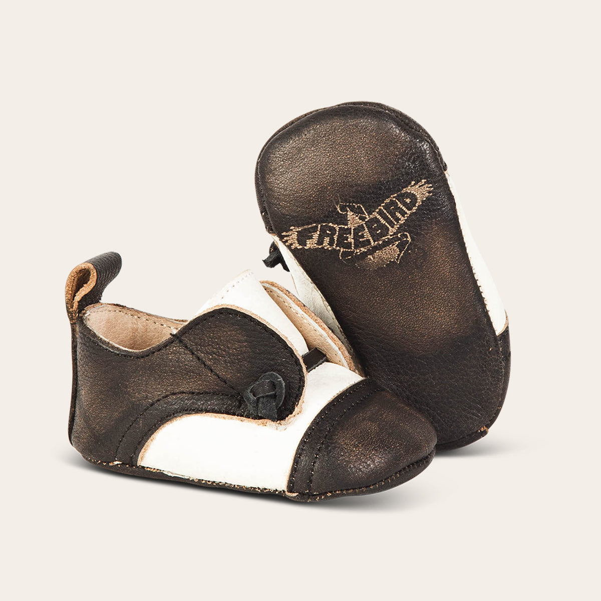 Side view showing decorative knotted leather lace and soft leather imprinted sole on FREEBIRD infant baby Mabel taupe leather shoe
