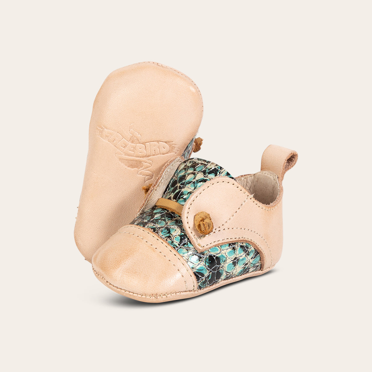 Side view showing decorative knotted leather lace and soft leather imprinted sole on FREEBIRD infant baby Mabel turquoise croco leather shoe