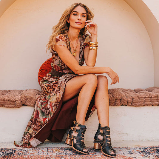 FREEBIRD women's Bradshaw black leather sandal with adjustable gold buckle hardware, stud embellishments and cut out detailing. Finished on a lifted high heel lifestyle. 