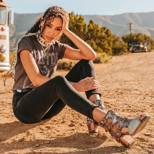 FREEBIRD women's Bradshaw blue/silver two-toned leather sandal with adjustable gold buckle hardware, stud embellishments and cut out detailing. Finished on a lifted high heel lifestyle