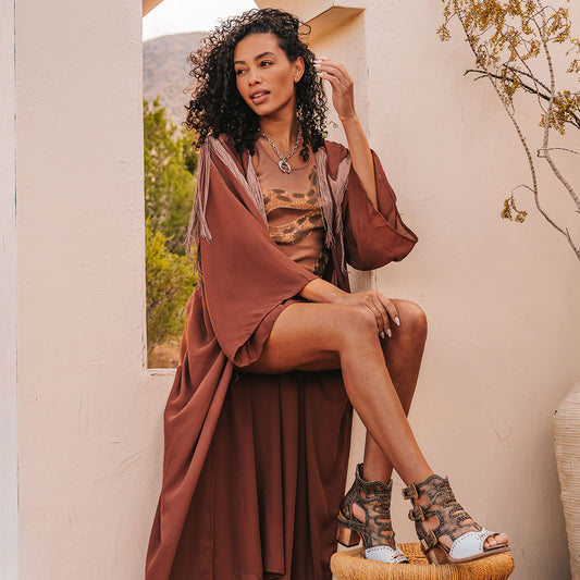 FREEBIRD women's Bradshaw white/gold two-toned leather sandal with adjustable gold buckle hardware, stud embellishments and cut out detailing. Finished on a lifted high heel lifestyle