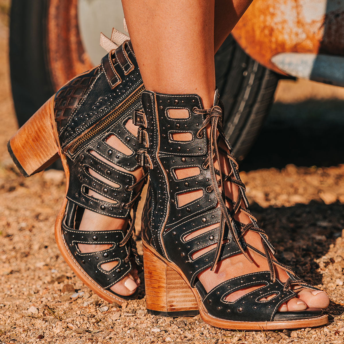 FREEBIRD women's BUD black leather sandal with laser-cut heel paneling, front leather lacing, silver stud detailing and a lifted heel