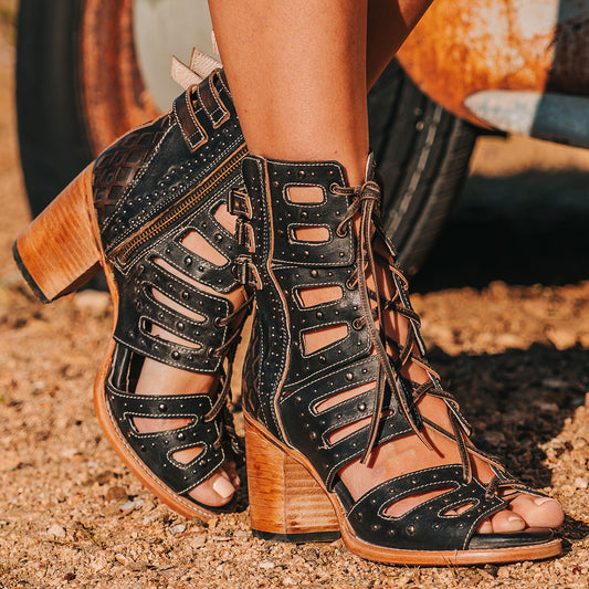 FREEBIRD women's BUD black leather sandal with laser-cut heel paneling, front leather lacing, silver stud detailing and a lifted heel