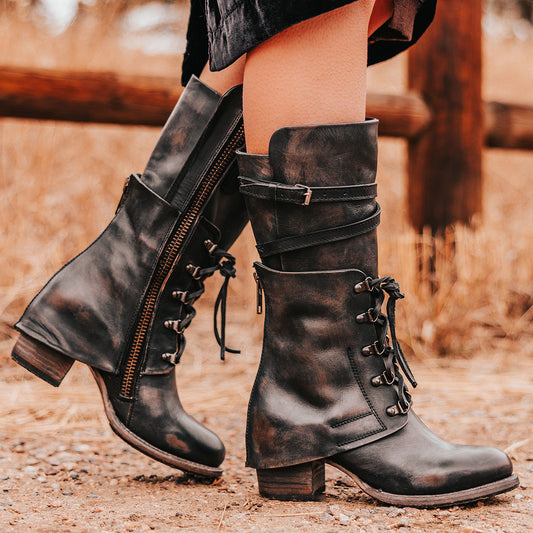 FREEBIRD women's Caboose black leather boot featuring a leather shaft overlay with adjustable front lacing, zig-zag buckling and a full inside working brass zipper 