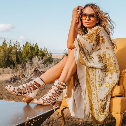 FREEBIRD women's Cashmere off white leather sandal with gold adjustable shaft straps, a structured double layer leather detailing and stud embellishments lifestyle
