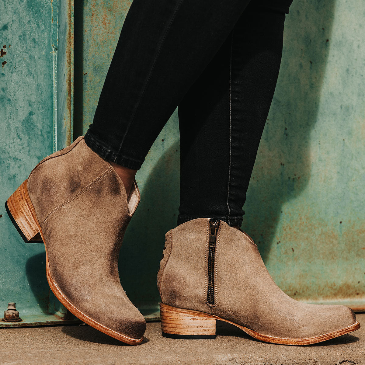 Beige suede HIPPY booties featuring a low heel, almond toe, sleek vamp, and a side brass zipper closure.