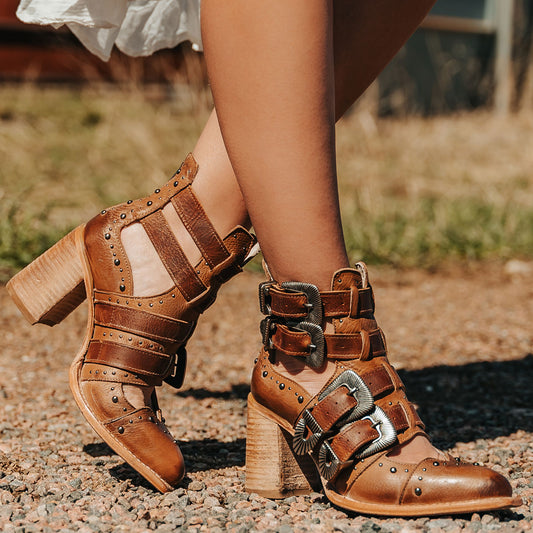 FREEBIRD women's Judge tan leather bootie with engraved belts, contrating metal embellishments and a stacked heel