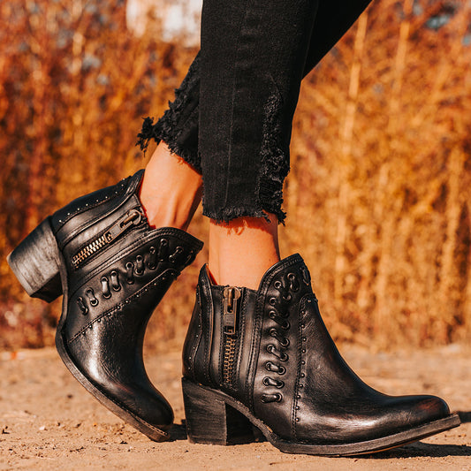 FREEBIRD women's Ryder black leather bootie with inside zip closures, eyelet whip stitch leather detailing and an almond toe.