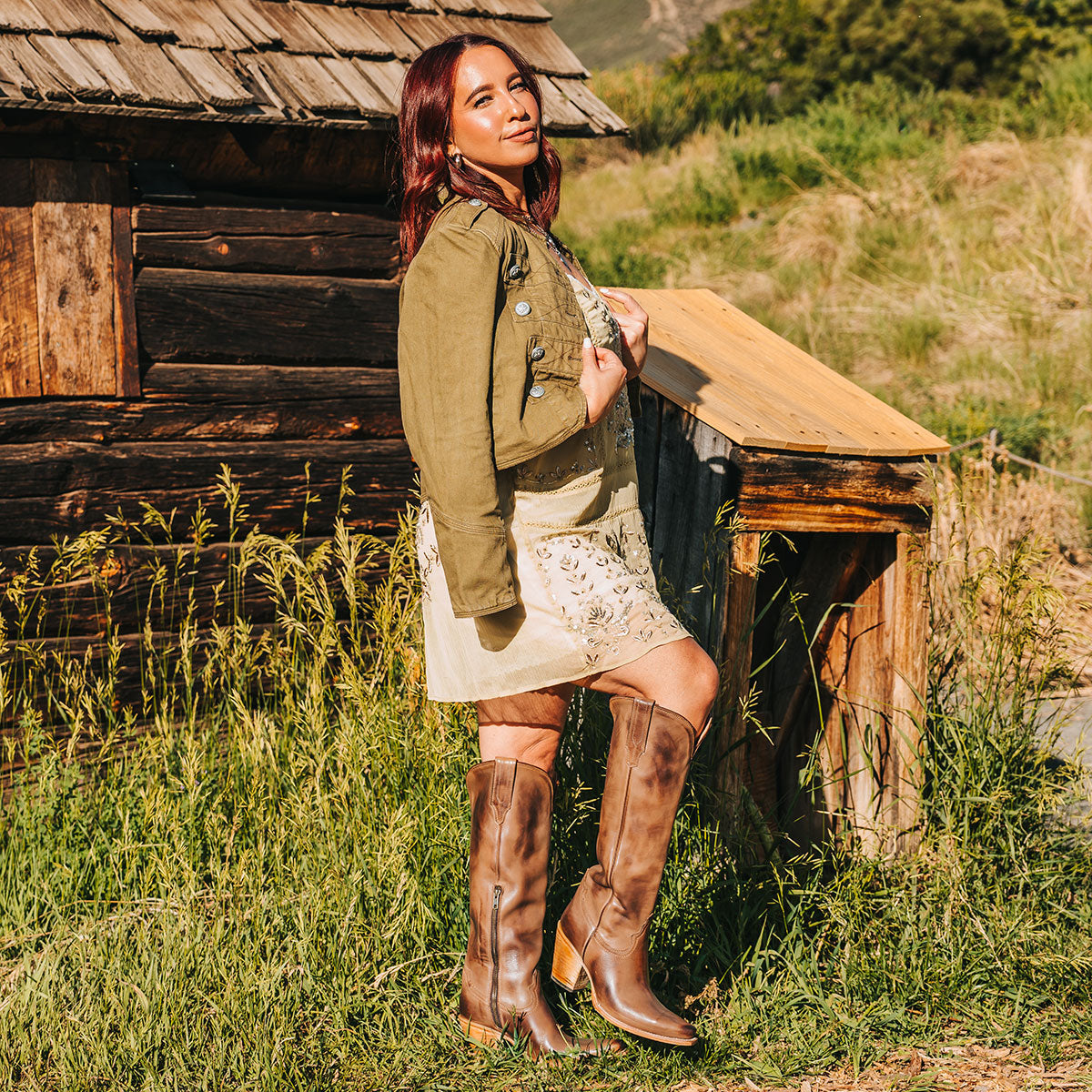 Thunderbird beige tall leather boots styled beside a rustic cabin