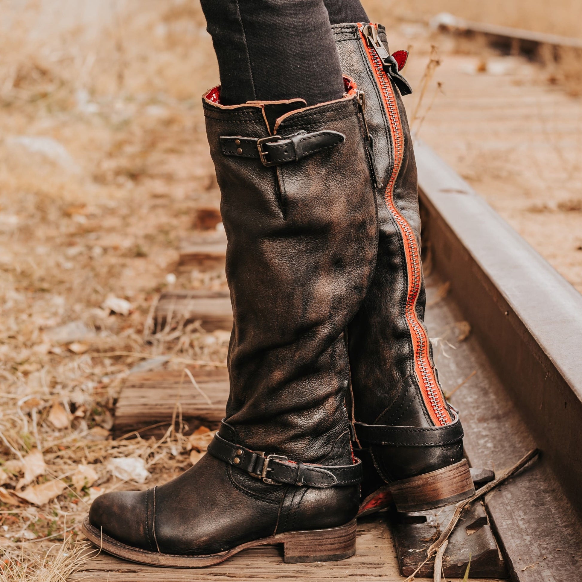 FREEBIRD women's Roadey black tall construction boot with double buckle detailing and signature red tracked zipper