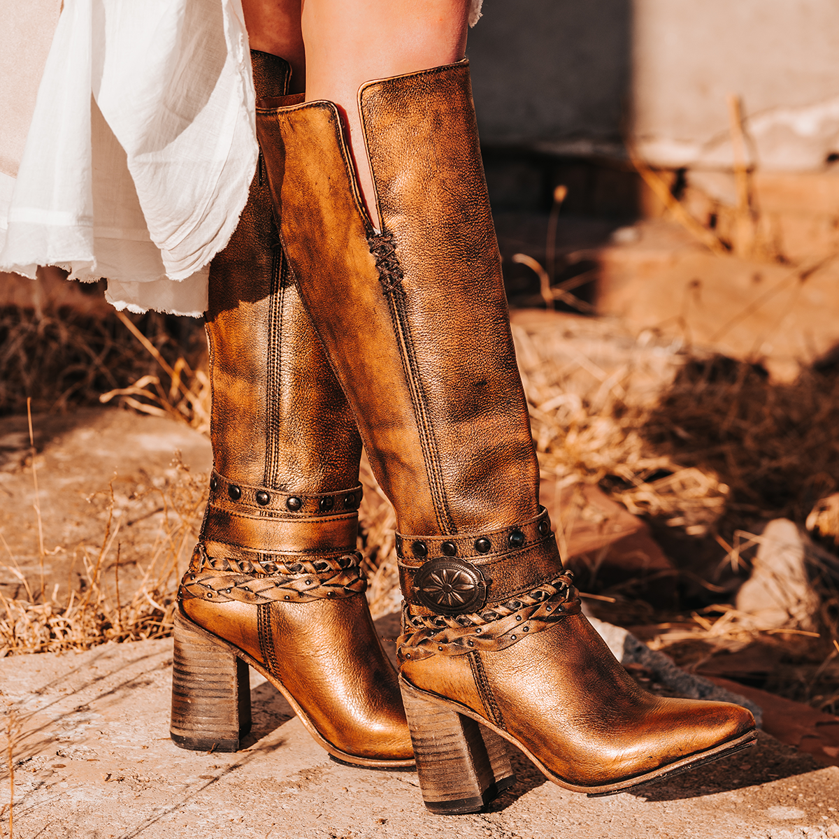 FREEBIRD women's Juniper bronze heeled boot featuring a pointed toe, back zip closure, and braided and studded ankle straps