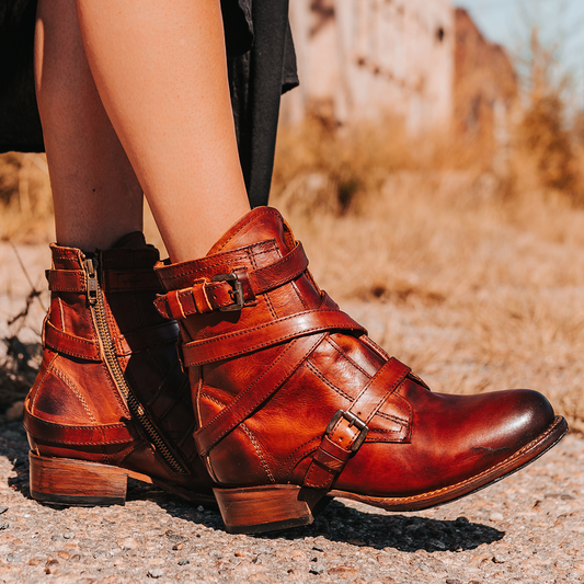 FREEBIRD women's Raine cognac full grain leather bootie with inside zip closure, wooden heel, and leather overlays with metal buckles