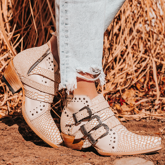 FREEBIRD women's WHILHELMINA white snake ankle bootie featuring engraved metal buckles, snip toe, and embellished stud detailing