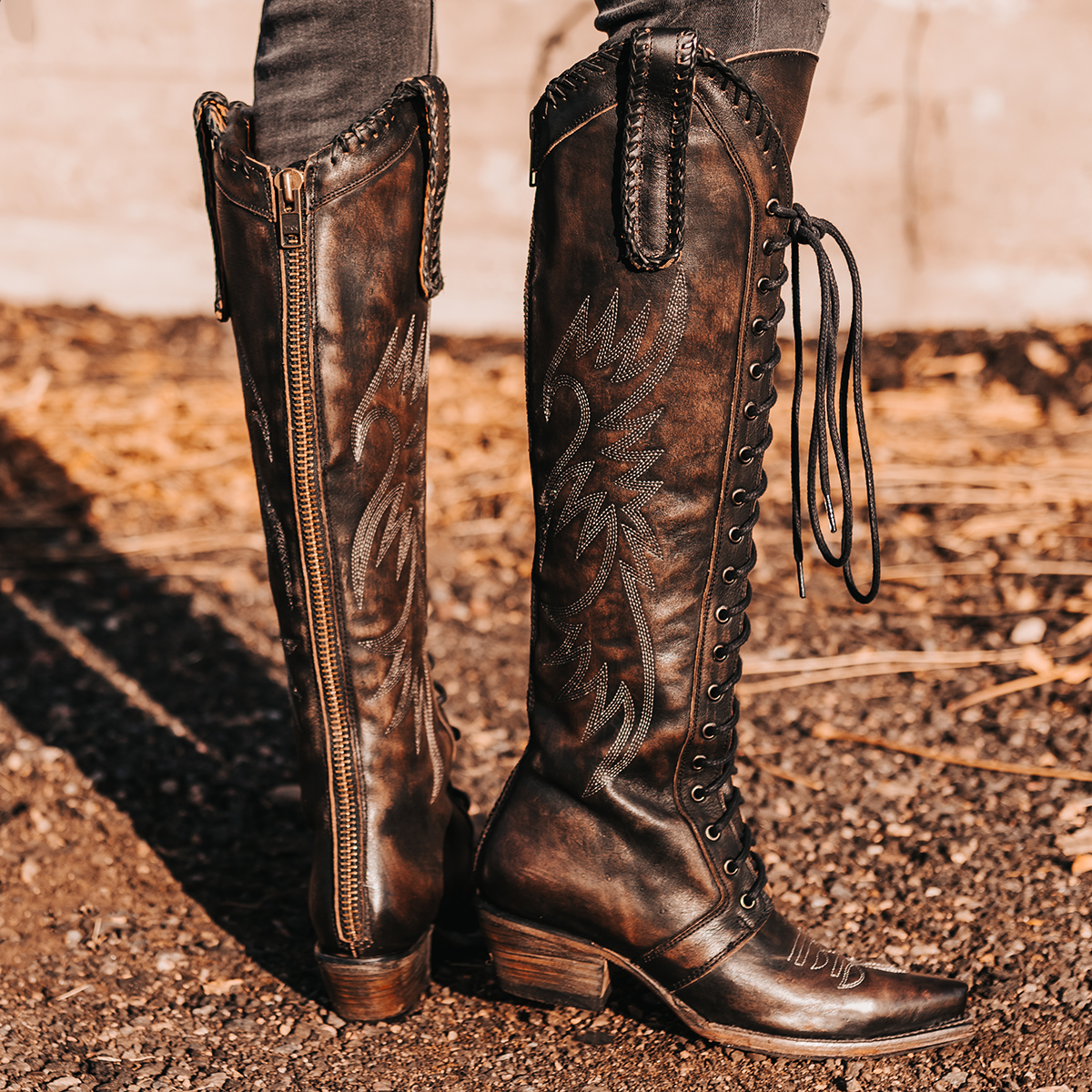 FREEBIRD women's Wilder black boot featuring a tall lace up shaft, contrasting stitch detailing, woven leather accents, and a back brass zip closure