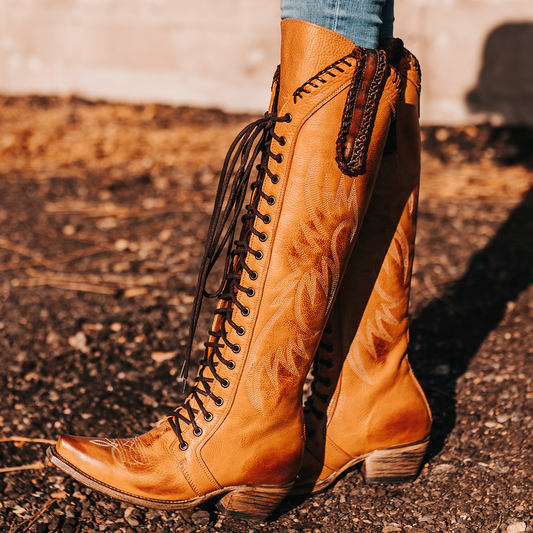 FREEBIRD women's Wilder wheat boot featuring a tall lace up shaft, contrasting stitch detailing, woven leather accents, and a back brass zip closure