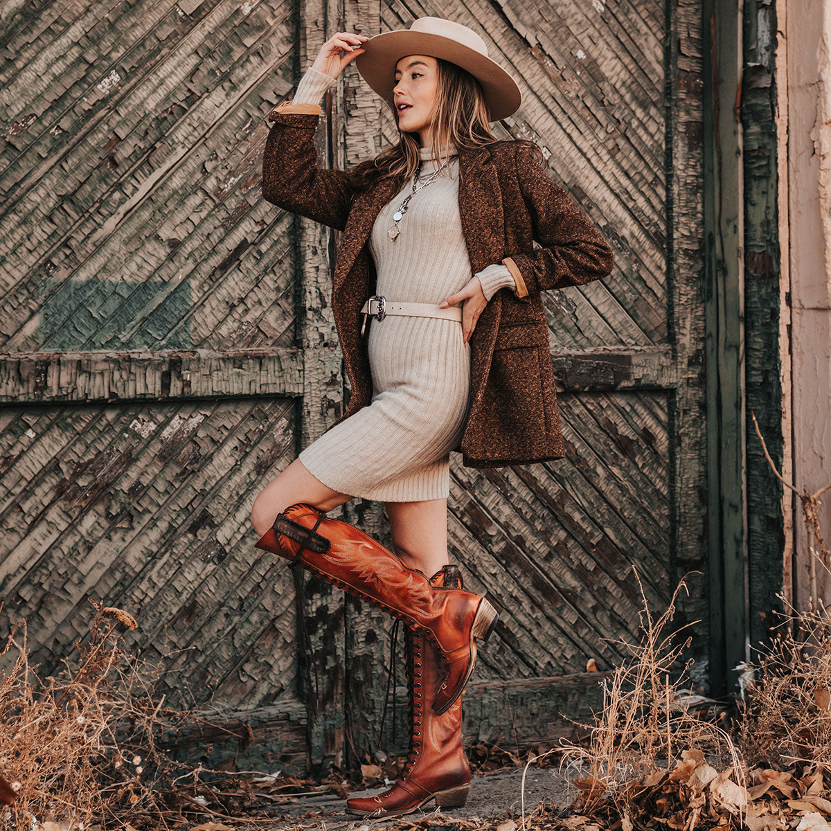 FREEBIRD women's Wilder whiskey boot featuring a tall lace up shaft, contrasting stitch detailing, woven leather accents, and a back brass zip closure lifestyle