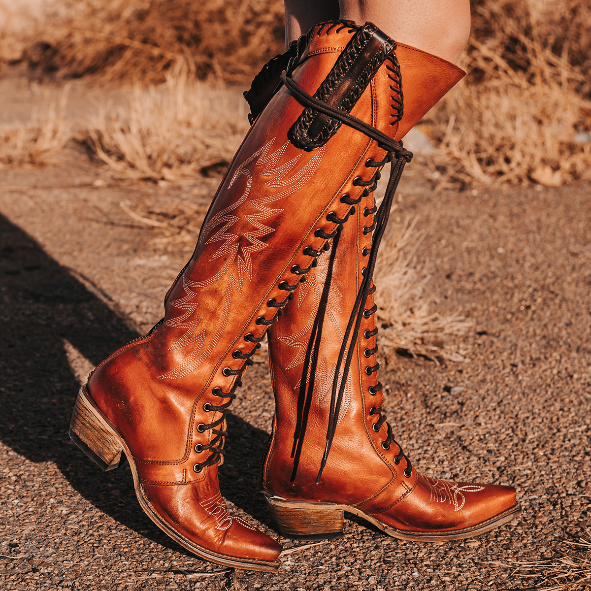 FREEBIRD women's Wilder whiskey boot featuring a tall lace up shaft, contrasting stitch detailing, woven leather accents, and a back brass zip closure