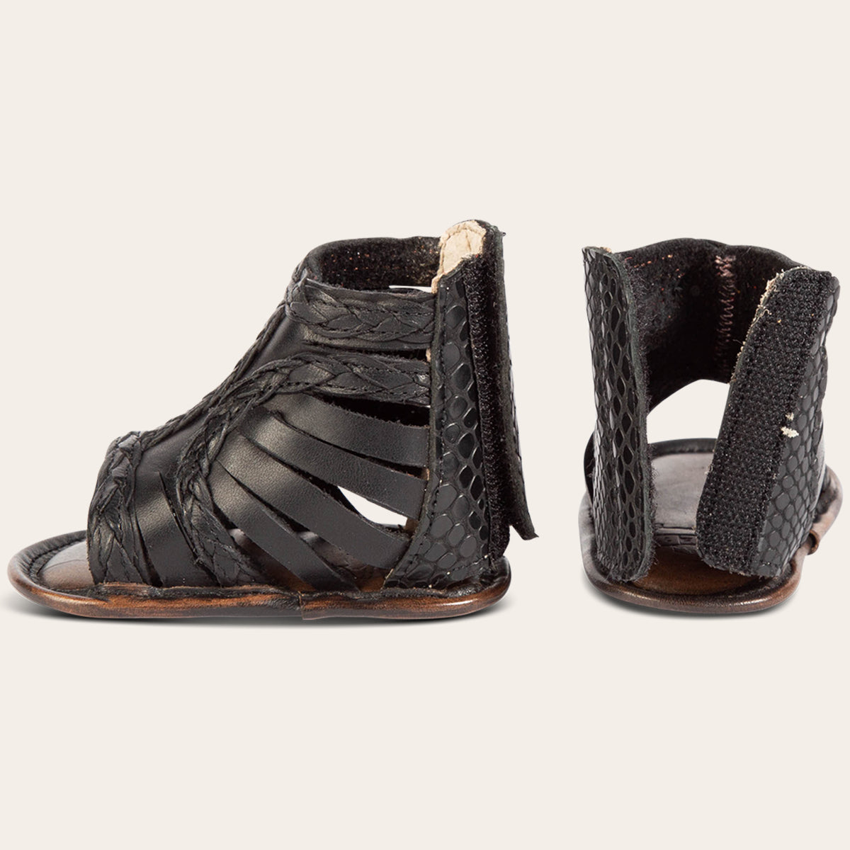 side and back view showing laser-cut leather, braided accents and embossed leather back velcro panel on FREEBIRD infant baby bela black leather sandal