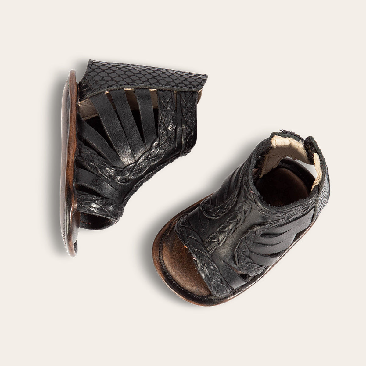 top view showing laser-cut leather, braided accents an embossed leather back velcro panel on FREEBIRD infant baby bela black leather sandal