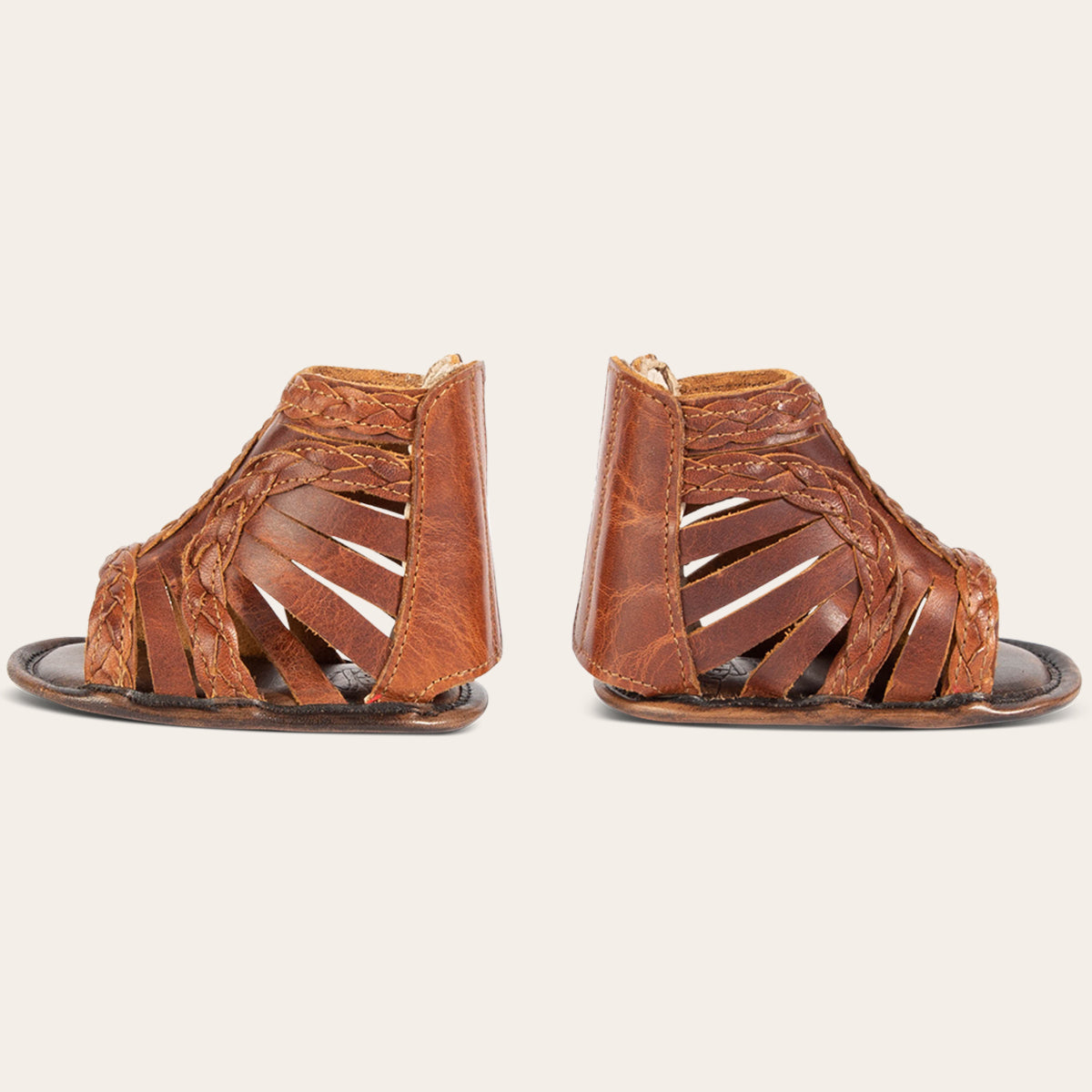 side view showing laser-cut leather, braided accents and leather back velcro panel on FREEBIRD infant baby bela cognac leather sandal