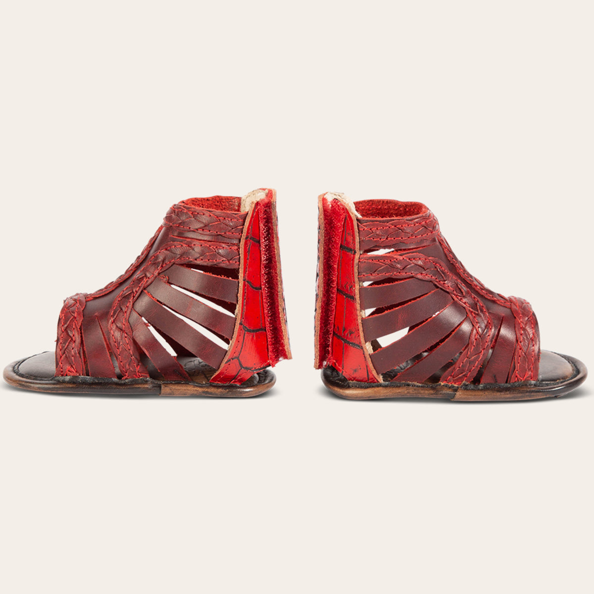 side view showing laser-cut leather, braided accents and embossed leather back velcro panel on FREEBIRD infant baby bela red leather sandal