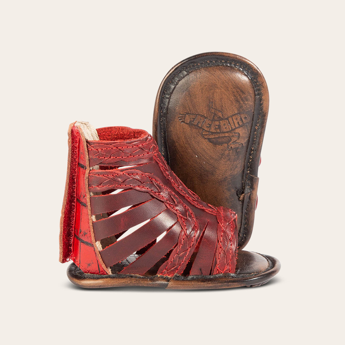 Front view showing laser-cut leather, braided accents and soft leather imprinted sole on FREEBIRD infant baby bela red leather sandal