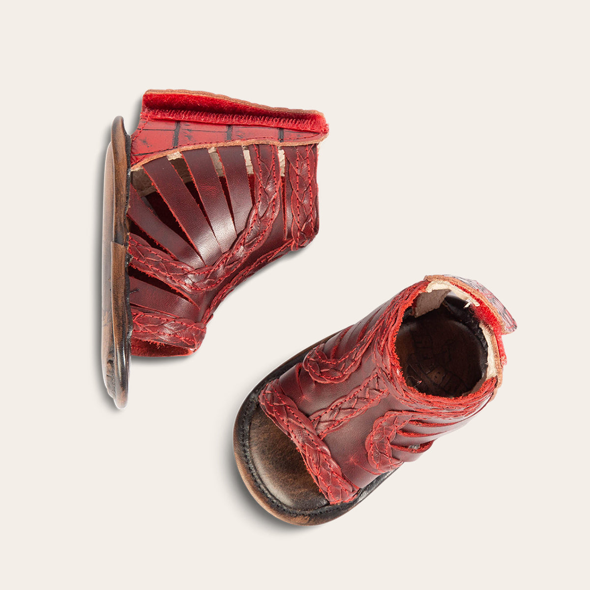 top view showing laser-cut leather, braided accents and embossed leather back velcro panel on FREEBIRD infant baby bela red leather sandal