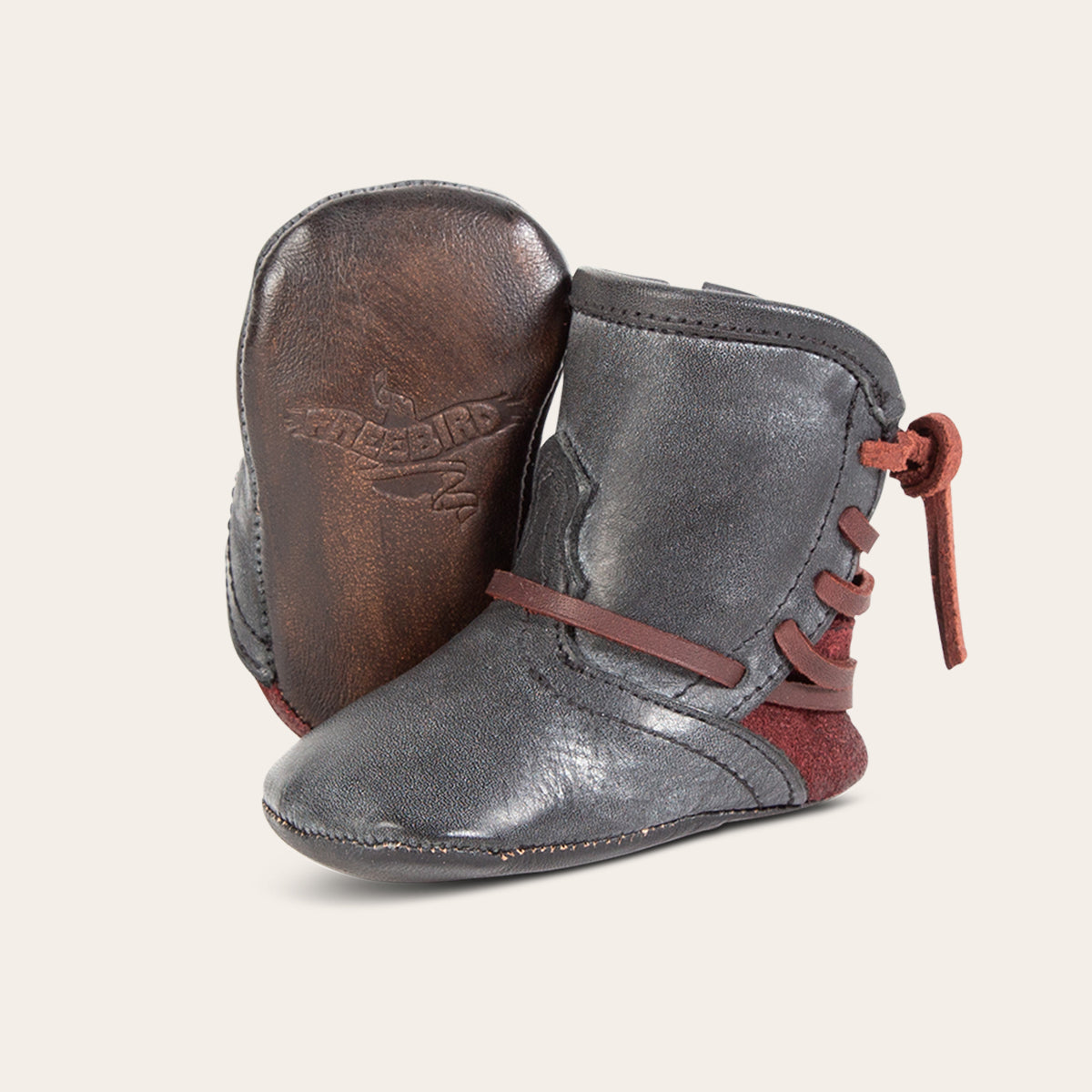 front view showing contrasting leather lace detailing and soft leather imprinted sole on FREEBIRD infant baby coal black leather bootie 