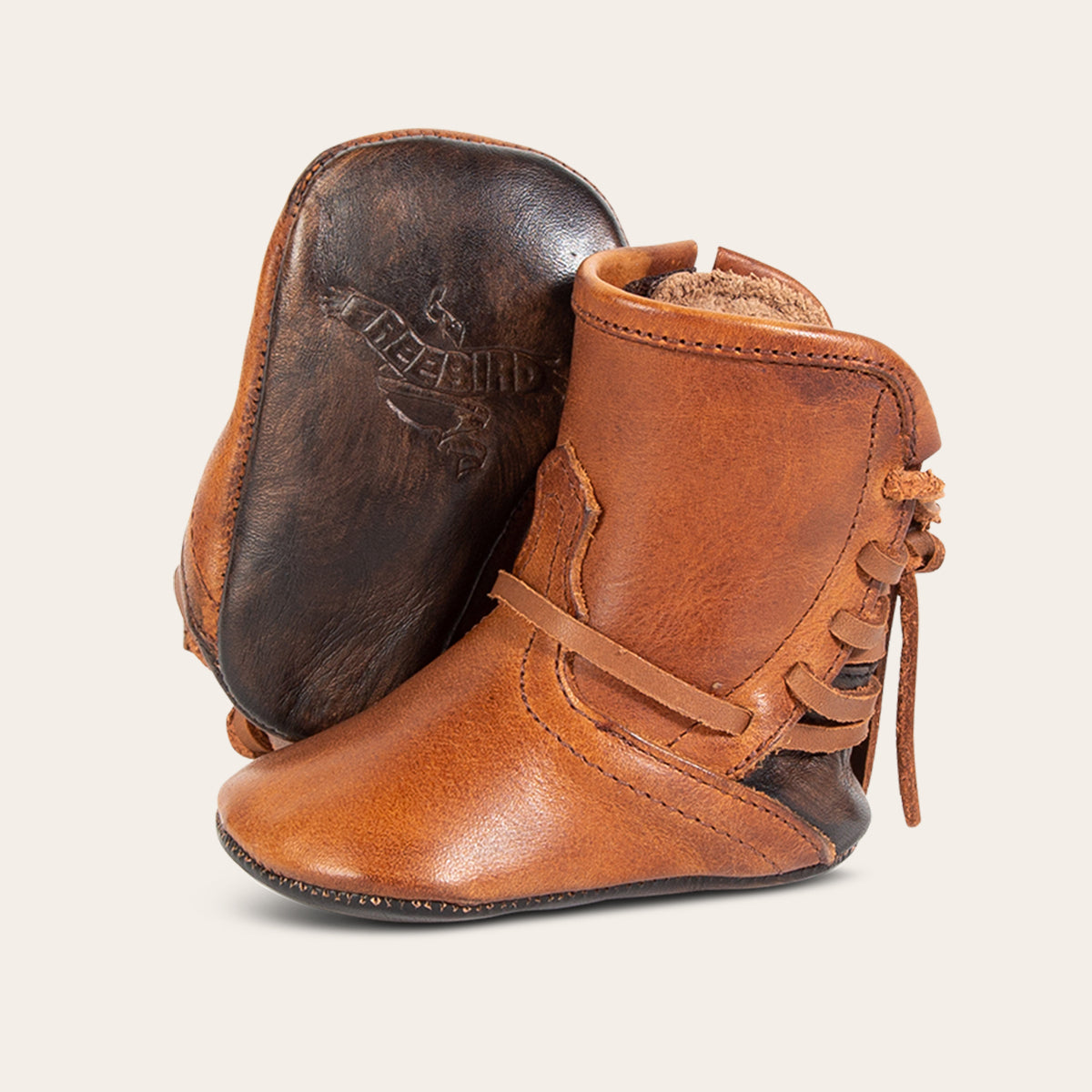 front view showing leather lace detailing and soft leather imprinted sole on FREEBIRD infant baby coal cognac leather bootie 