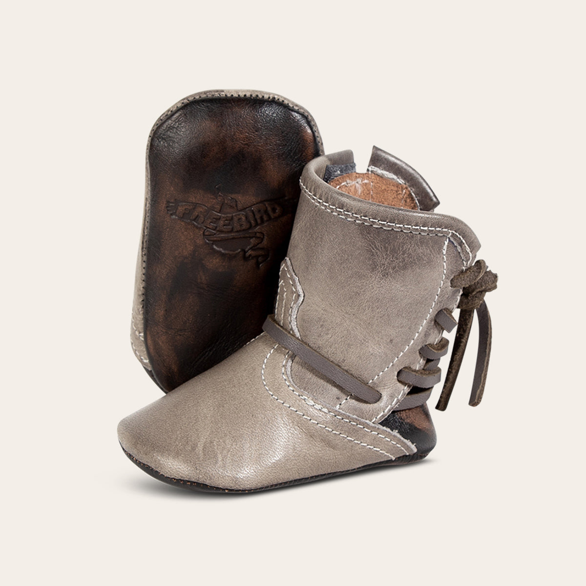 front view showing contrasting leather lace detailing and soft leather imprinted sole on FREEBIRD infant baby coal stone leather bootie 