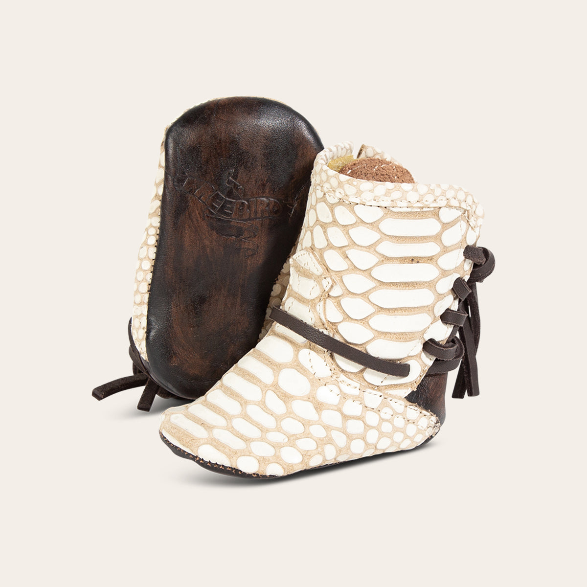 front view showing contrasting leather lace detailing and soft leather imprinted sole on FREEBIRD infant baby coal white snake leather bootie 