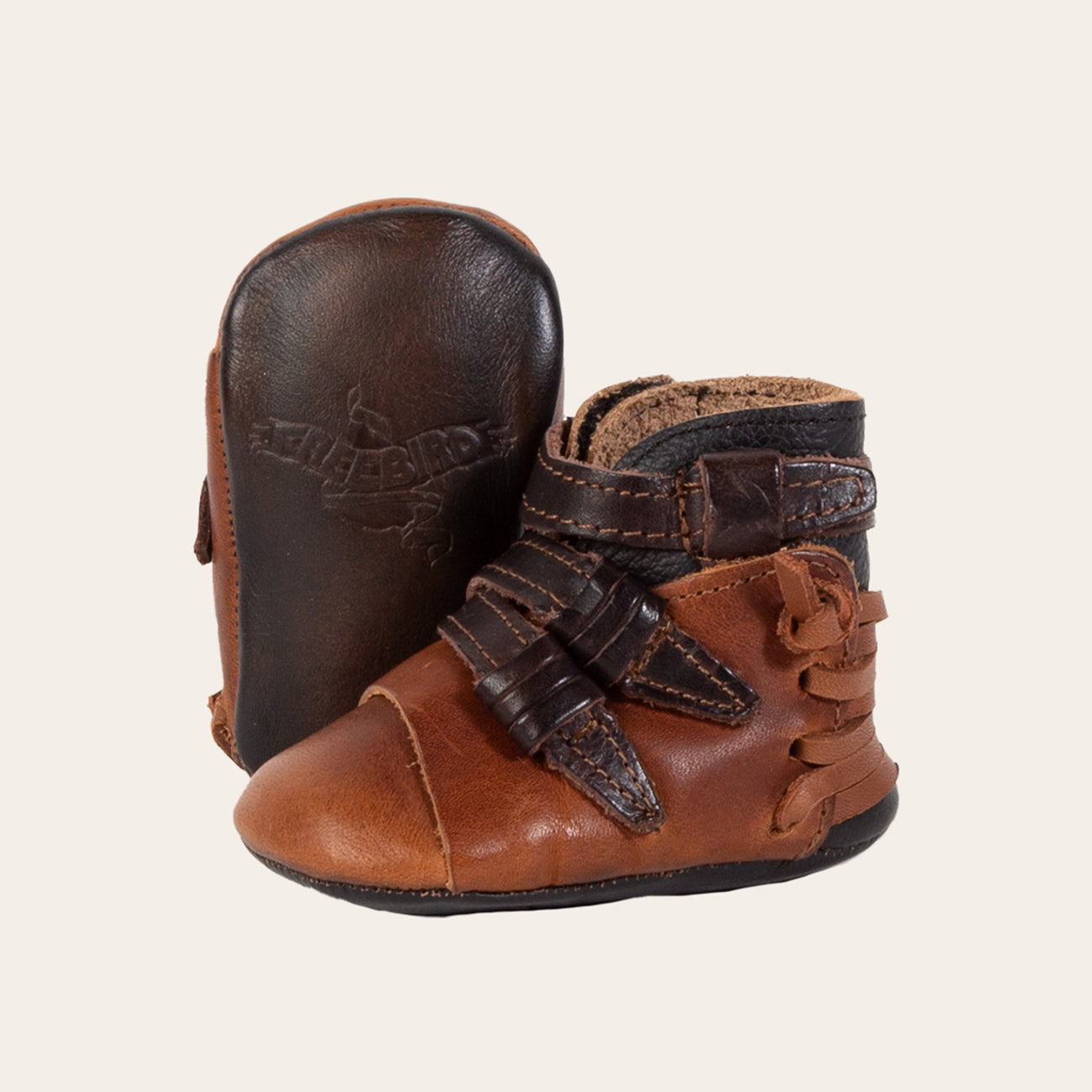front view showing contrasting leather side strap detailing and soft leather imprinted sole on FREEBIRD infant baby crue cognac leather bootie