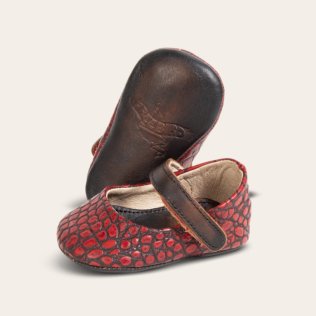 side view showing top leather strap and soft leather imprinted sole on FREEBIRD infant baby jane red croco leather shoe