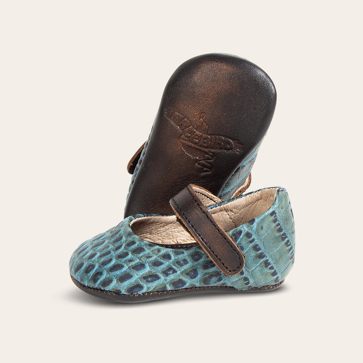 Side view showing leather strap detailing and soft leather imprinted sole on FREEBIRD infant baby jane turquoise leather shoe