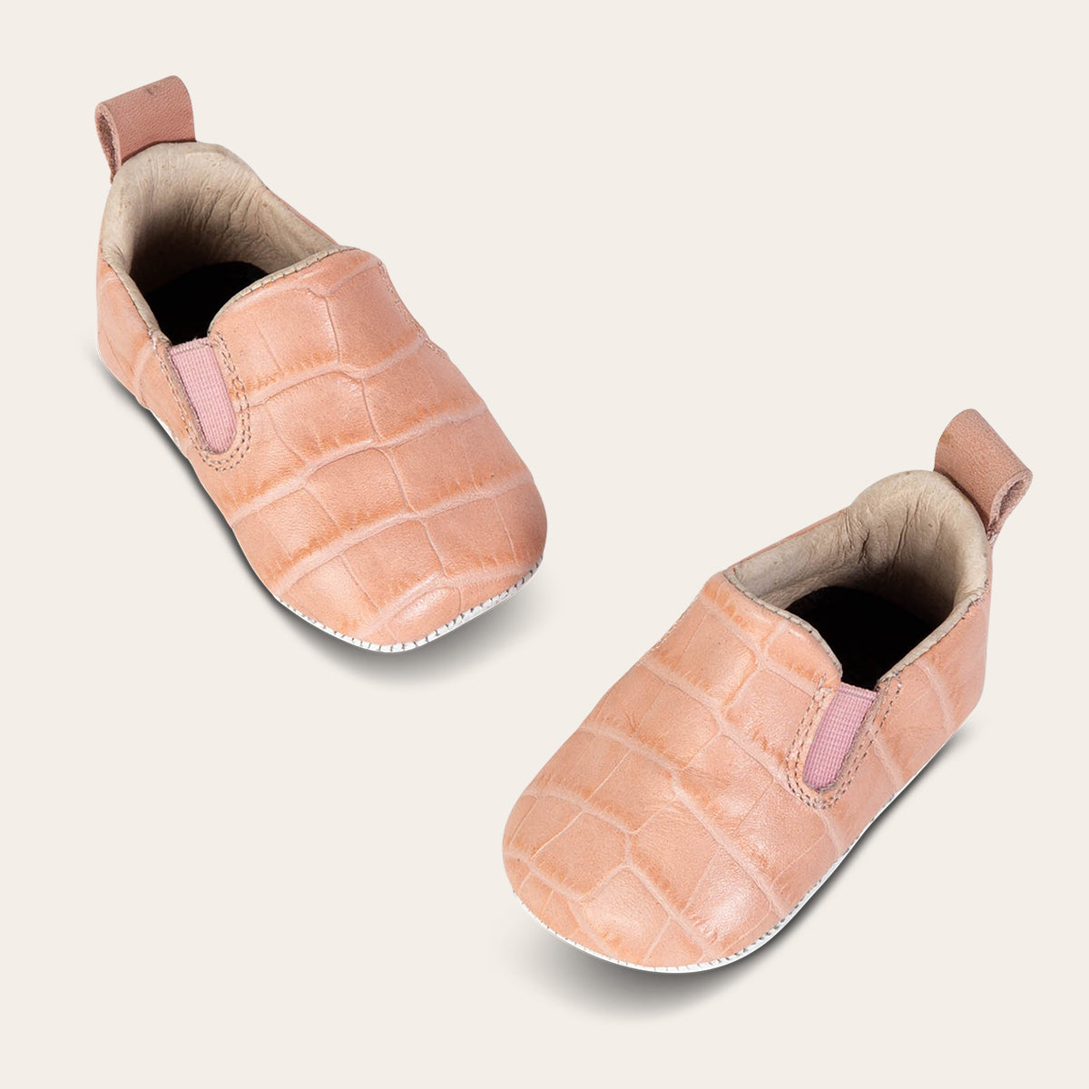 top view showing heel pull tab and side elastic panel on FREEBIRD infant baby kicks pink croco leather shoe