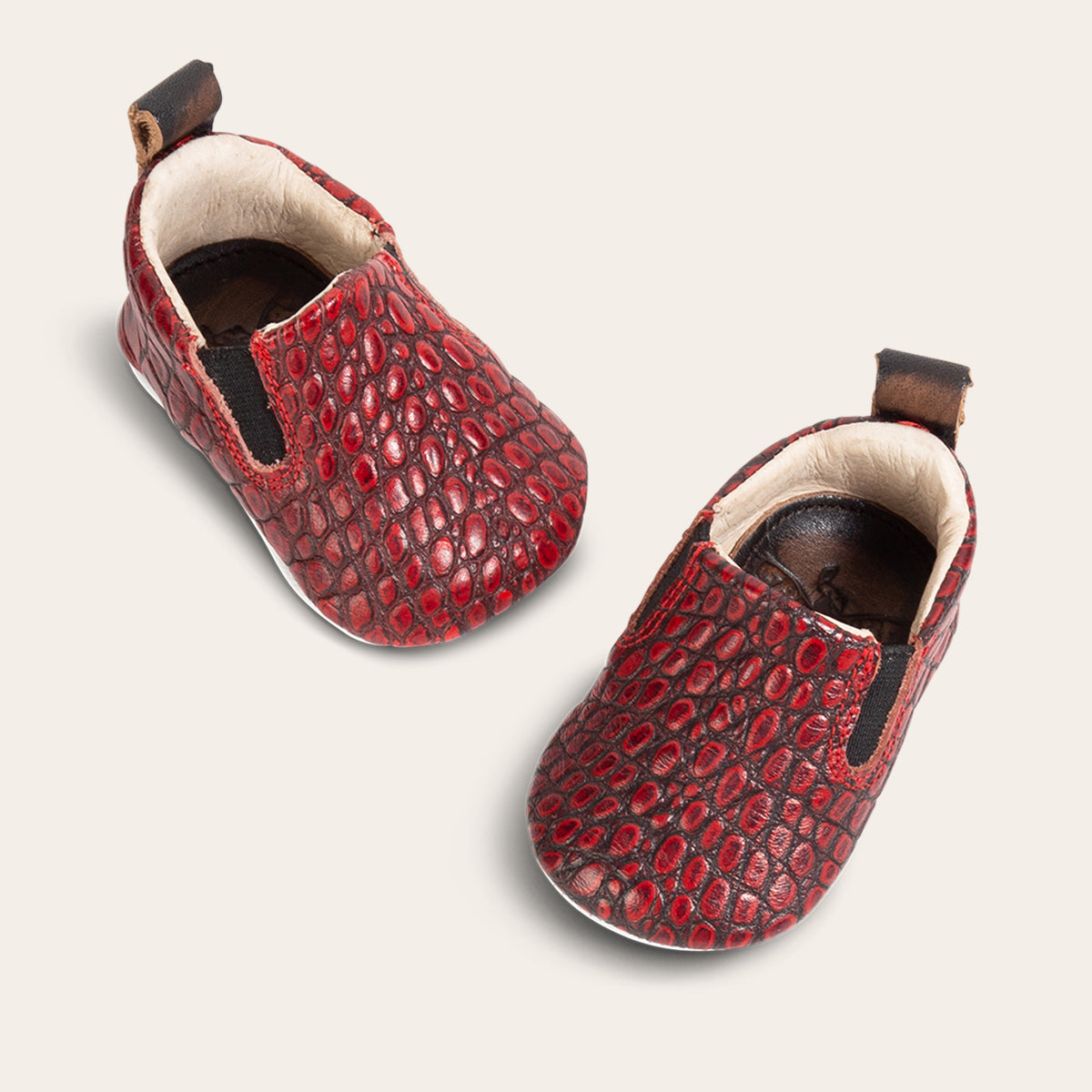 top view showing heel pull tab and side elastic panel on FREEBIRD infant baby kicks red croco leather shoe