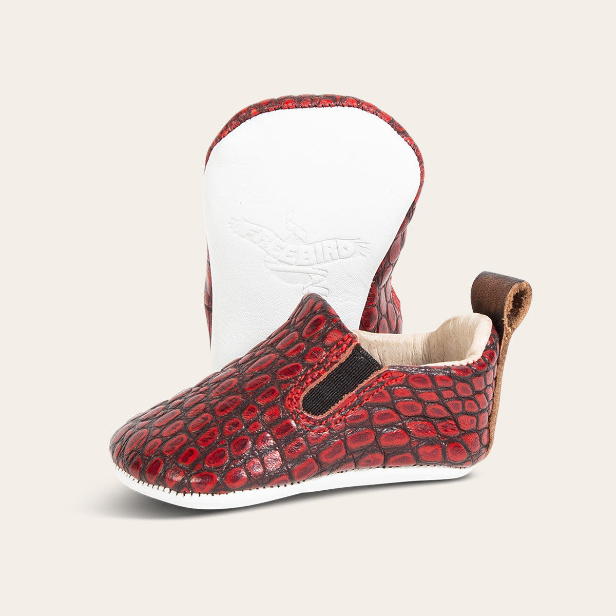 front view showing pull tab and side elastic panel and soft leather imprinted sole on FREEBIRD infant baby kicks red croco leather shoe