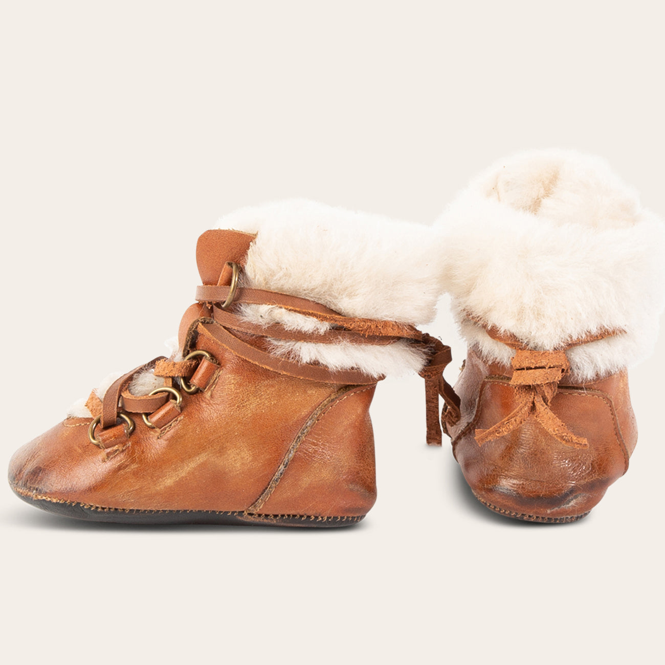side and back view showing shearling lining and contrasting leather lace detailing on FREEBIRD infant baby Norway cognac leather bootie