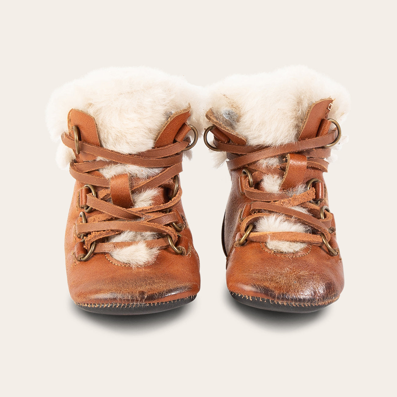 front view showing shearling lining and contrasting leather lace detailing on FREEBIRD infant baby Norway cognac leather bootie