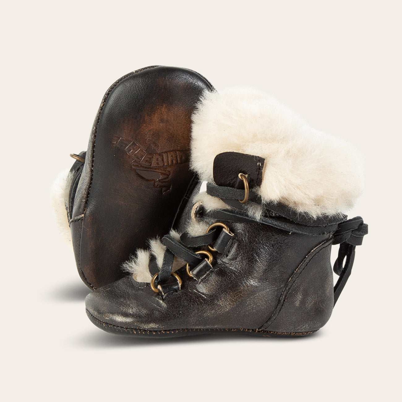 Side view showing shearling lining and contrasting leather lace detailing and soft leather imprinted sole on FREEBIRD infant baby Norway dark olive leather bootie