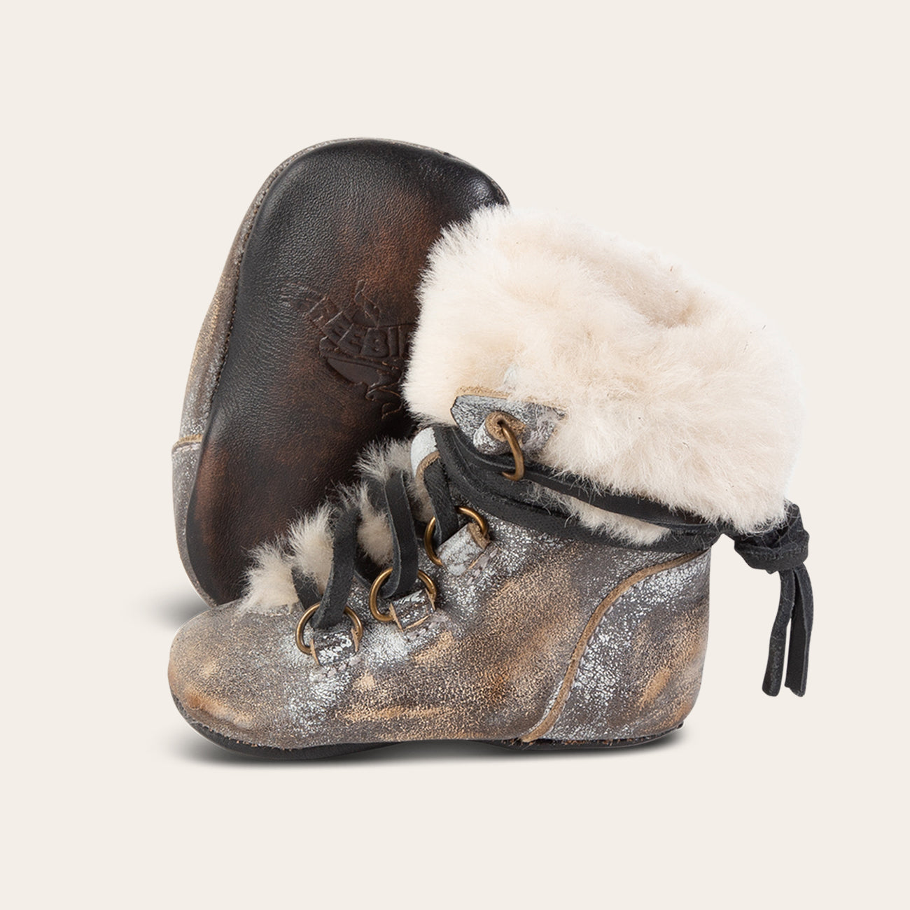 Side view showing shearling lining and contrasting leather lace detailing and soft leather imprinted sole on FREEBIRD infant baby Norway ice leather bootie