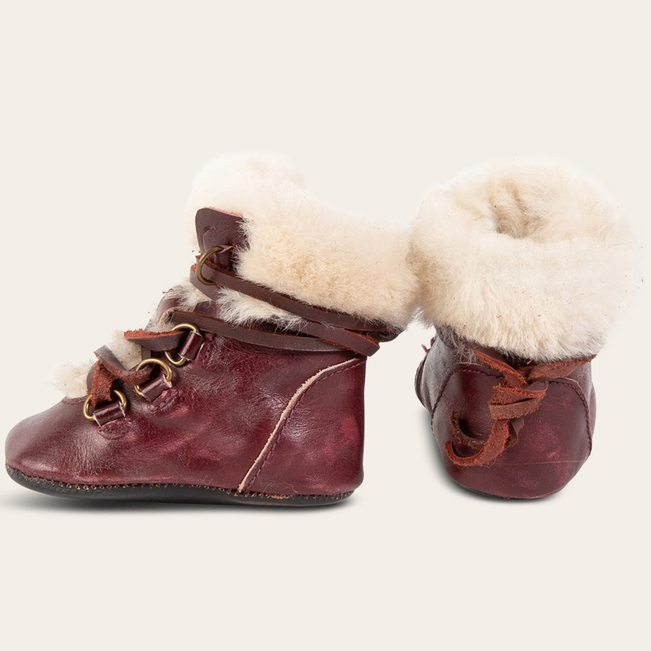 front and side view showing shearling lining and contrasting leather lace detailing on FREEBIRD infant baby Norway wine leather bootie