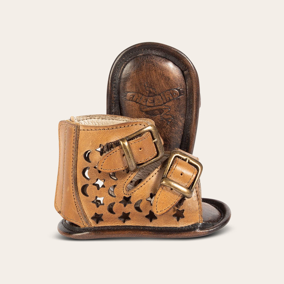 side view showing laser-cut leather, embossed fashion straps, back velcro panel and soft leather imprinted sole on FREEBIRD infant baby teresa tan leather sandal