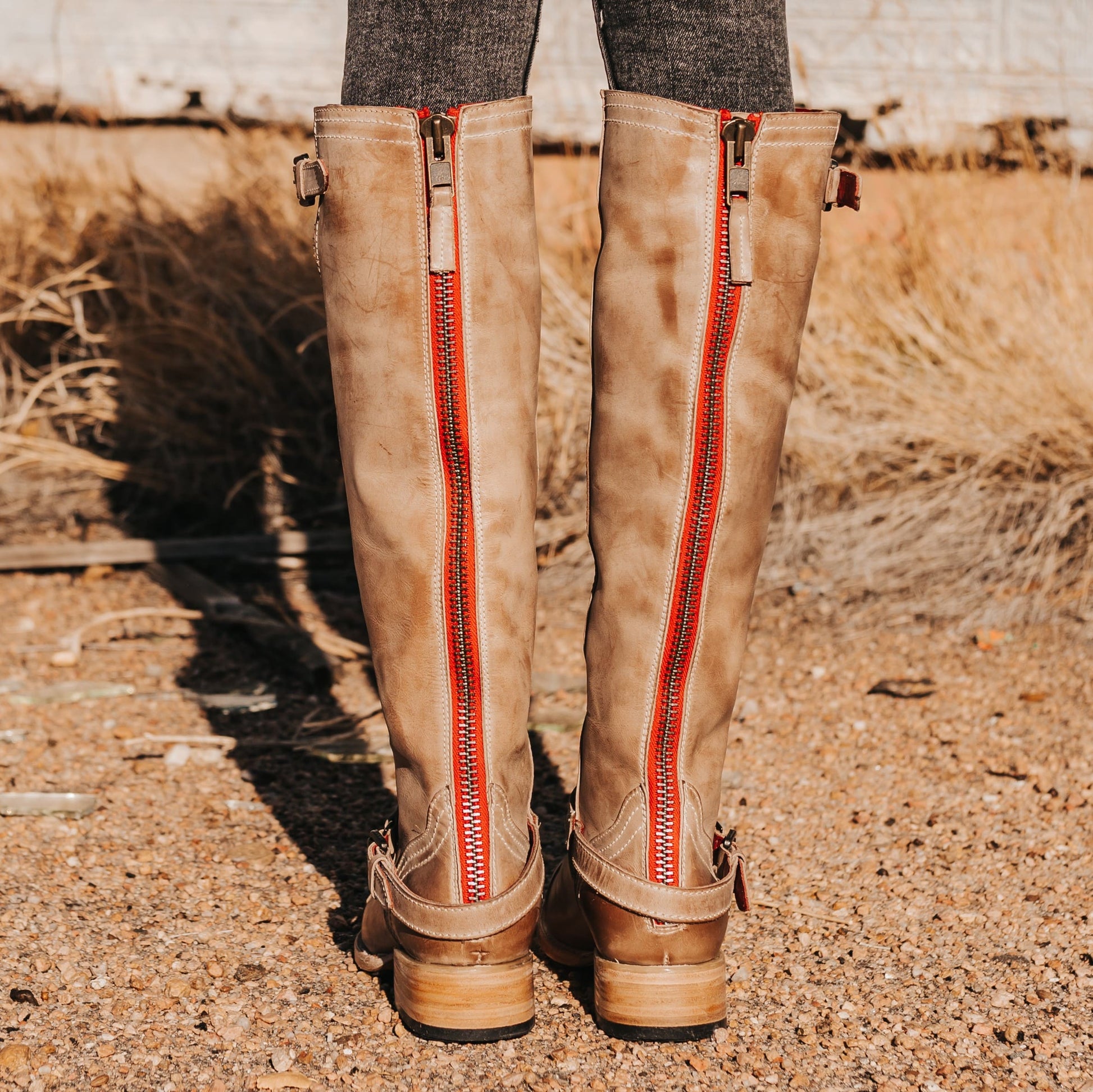 FREEBIRD women's Roadey taupe tall construction boot with double buckle detailing and signature red tracked zipper